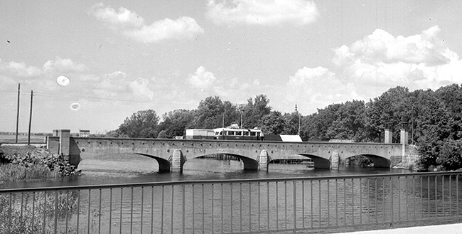 Järnvägsbron över Helgeå mellan Långebro och Kristianstad. Året är 1941-1944, gengasdriven CHJ rälsbuss med släp rullar över bron och vidare till Kristianstad.