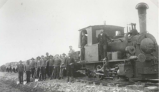 WbJ byggnad. Entreprenren Saabye & Lerche's anlggningslok Hanomag 4573 1906 B. Grustg med rallare uppstllda framfr vagnarna.