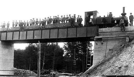 VSBJ nybyggda viadukt ver SJ linjen i Sknninge 1913. Fr banbygget inhyrt SRJ lok 33 med ett arbetstg har stannat p viadukten fr att fotografen ska kunna freviga hndelsen.